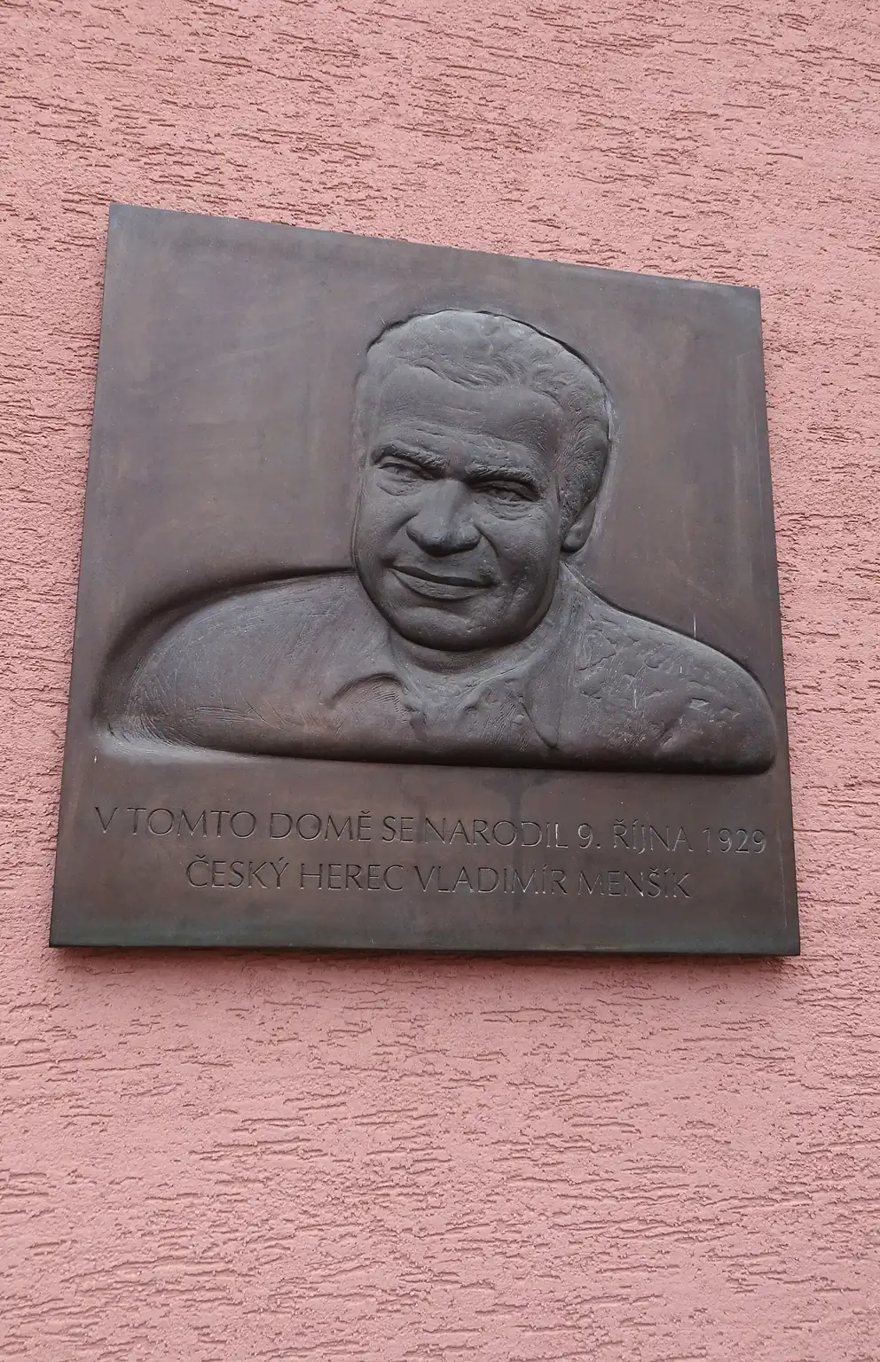 Pamětní deska Vladimíra Menšíka v Ivančicích na fotografii z roku 2025. Reliéfní podobizna, nikoli archivní portrét herce.