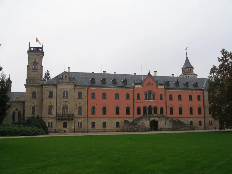 Zámek Sychrov na archivní fotografii; pohled na průčelí a park.